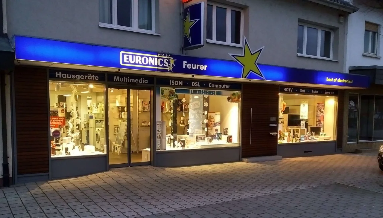 Unser Ladengeschäft in der Rheinstraße 23 in Rheinau am Abend mit beleuchteten Schaufenstern